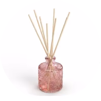 Difusor de aroma con varillas en frasco de vidrio rosa.